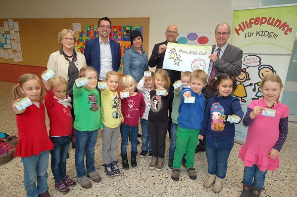 Die Kinder aus der „Delfinklasse“ in der Hövelhofer Kirchschule haben ihre „Meine-Hilfe-Card“ schon ausgefüllt: v.l. Felina, Leonie, Maja, Sadie, Lena, Josefine, Diana, Simon, Lambert, Sara, Emma Hintere Reihe: v.l. Angelika Reddeker (stellvertr. Leiterin Kirchschule), Carlos Tomé (Kreisjugendamt), Maike Dannewald (Jugendamt Stadt Paderborn), Christoph Stork (Caritas), Landrat Manfred Müller.